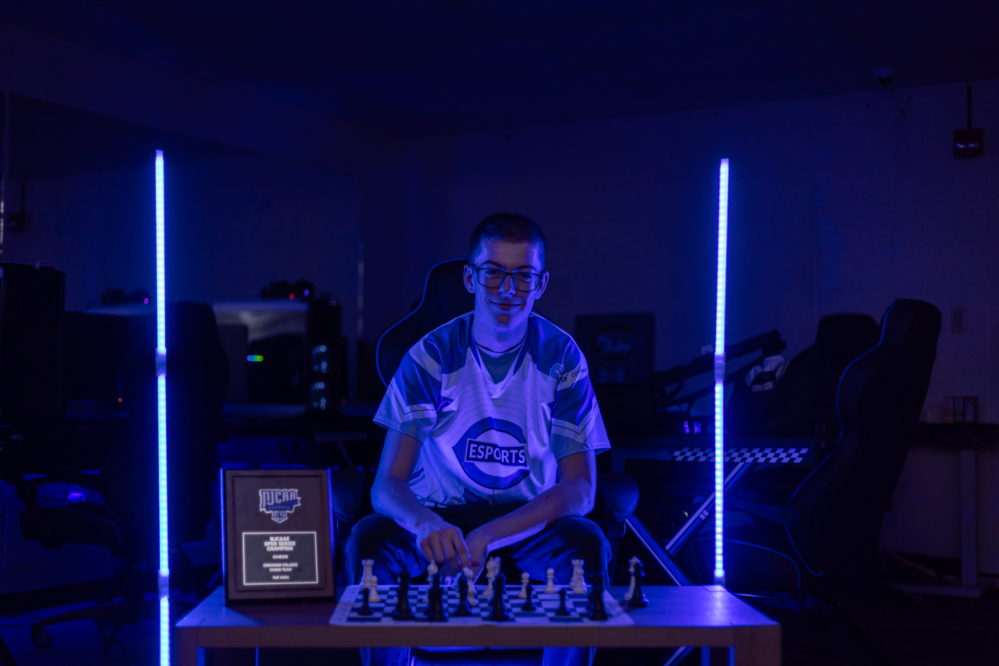 Jonathan Tribbey in blue light in front of chess board.